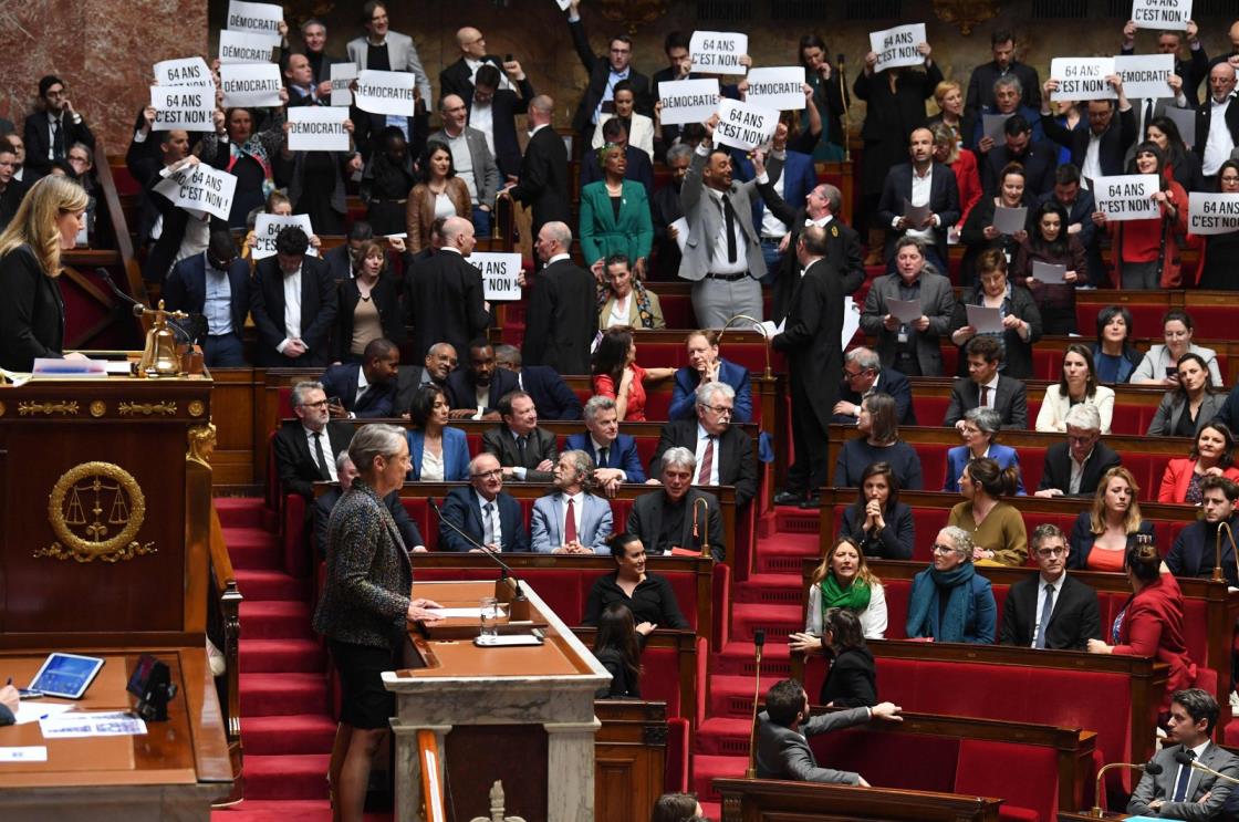 Members of Parliament of left-wing coalition NUPES (New People's Ecologic and Social Unio<em></em>n) hold placards during the speech of France's Prime Minister Elisabeth Borne (center), as she co<em></em>nfirms to force through pension law without parliament vote during a session on the government's pension reform at the lower house Natio<em></em>nal Assembly, in Paris, France, March 16, 2023. (AFP Photo)