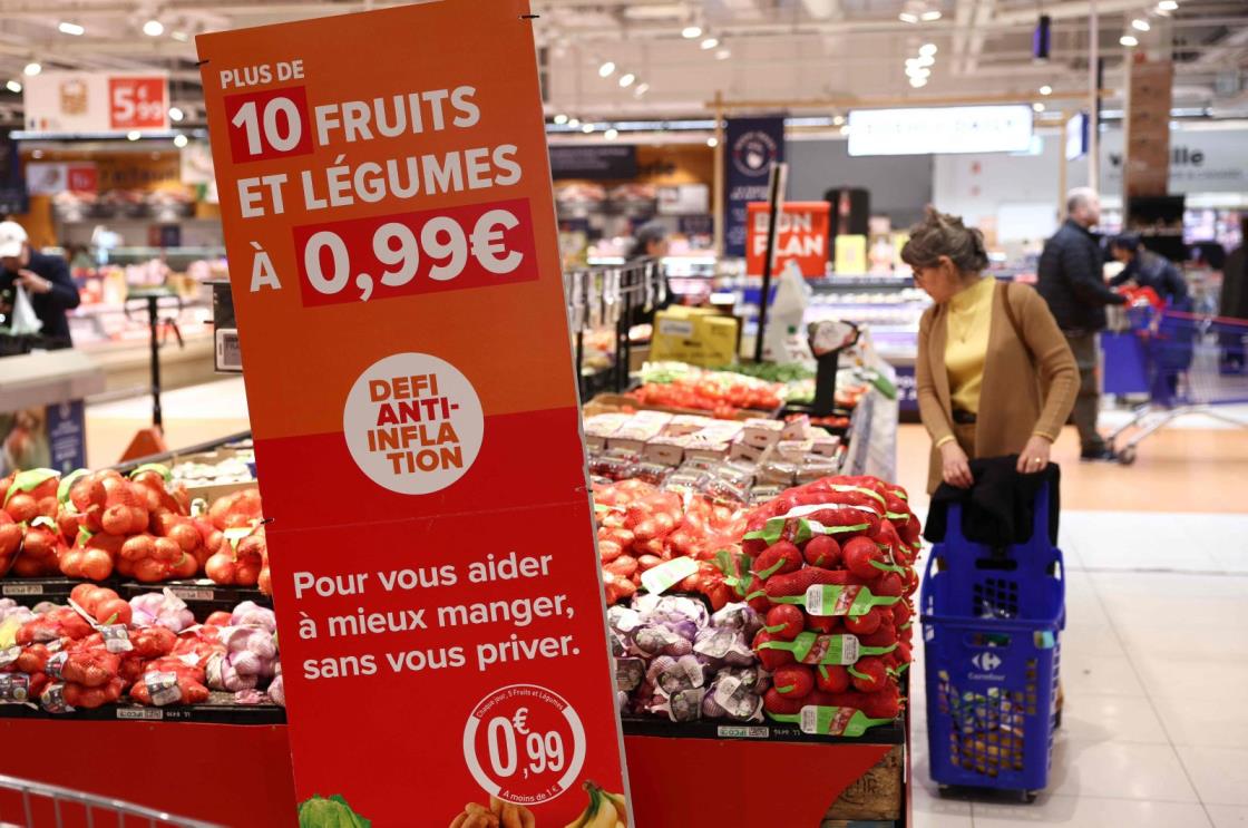 A customer looks at fruits et vegetables next to an information sign reading 