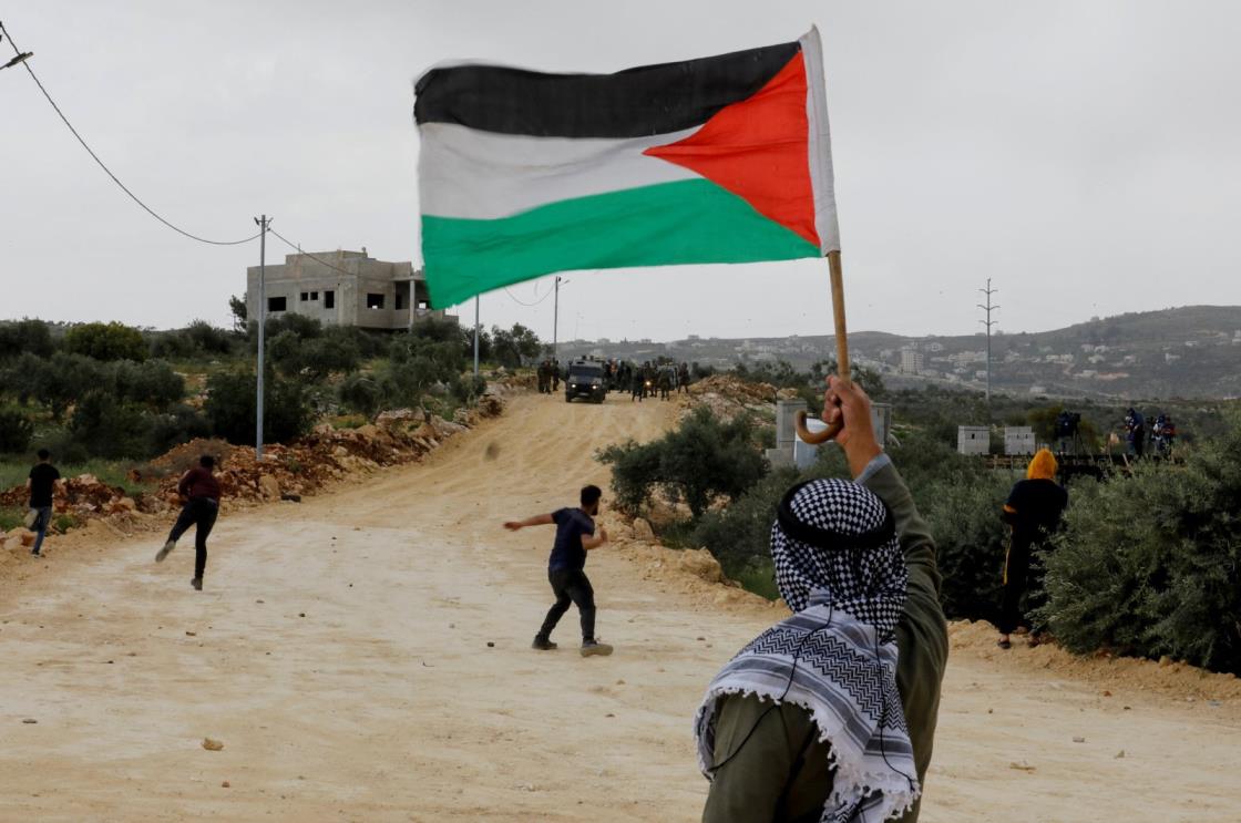 A demo<em></em>nstrator holds a Palestinian flag during clashes with Israeli forces at a protest against Israeli settlements, Nablus, in the Israeli-occupied West Bank, Palestine, April 10, 2023. (Reuters Photo)