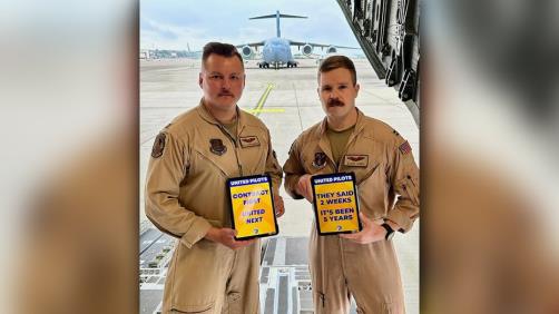 Military pilots hold signs in support of United Airlines pilots