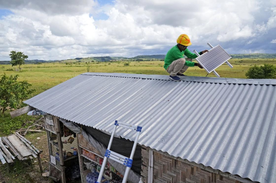 Anto<em></em>nius Makambombu, a worker of Sumba Sustainable Solutions performs maintenance work on a solar panel on the roof of a customer's shop in Laindeha village on Sumba Island, Indonesia, March 22, 2023. (AP Photo)