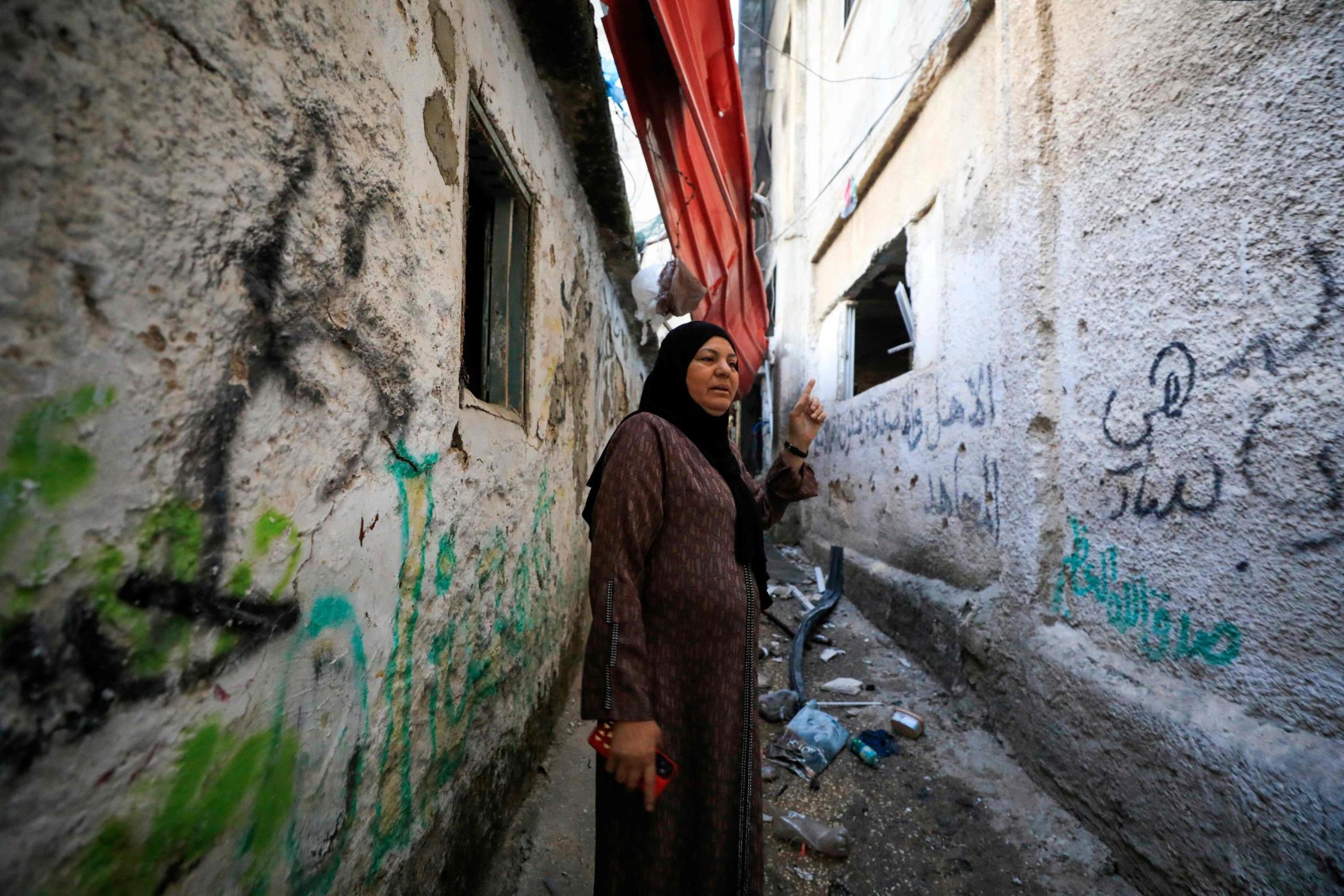 A Palestinian woman checks her damaged building following an Israeli army raid at the Balata refugee camp near the occupied West Bank city of Nablus, Palestine, May 22, 2023. (AFP Photo)